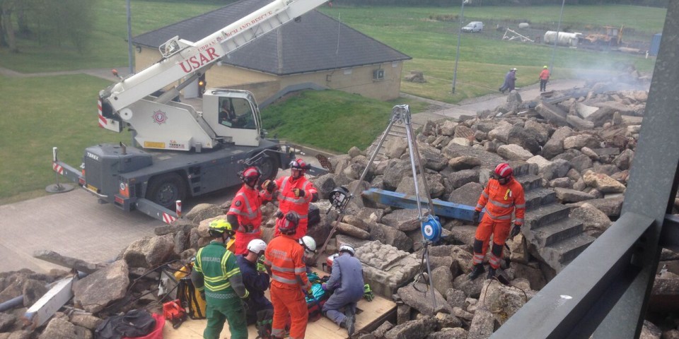 Team of emergency workers clearing rubble from a simulated training environment to save a casualty